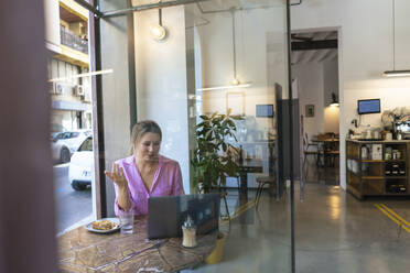 Freelancer talking on video call through laptop in cafe - JOSEF14726