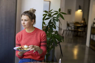 Smiling freelancer with plate of food sitting in cafe - JOSEF14746