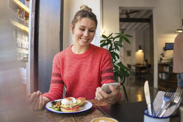 Glücklicher Freiberufler mit Smartphone im Café - JOSEF14773