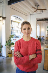 Young entrepreneur with arms crossed standing in cafe - JOSEF14775