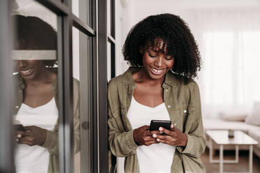 Smiling woman using smart phone at home - EBBF06924