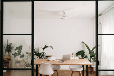 Desk and chairs arranged in home office seen through doorway - EBBF06936