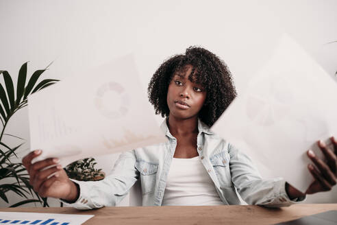 Young businesswoman comparing statistics data at home office - EBBF06967