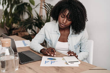 Businesswoman preparing data sitting at desk in home office - EBBF07016