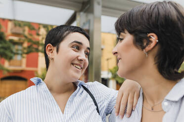 Lächelnde Frau mit Hand auf der Schulter einer lesbischen Freundin - JRVF03266