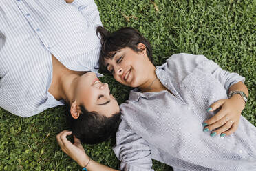 Romantic lesbian couple spending leisure time lying on grass - JRVF03273