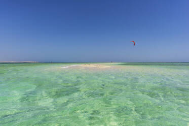Ägypten, Gouvernement Rotes Meer, Hurghada, Türkisfarbenes Wasser des Roten Meeres mit fliegendem Gleitschirm im Hintergrund - THAF03137