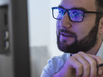 Smiling trader analyzing stock market data on computer screen - ABRF01015