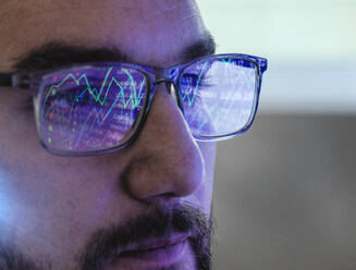 Trader wearing eyeglasses analyzing stock market data - ABRF01017