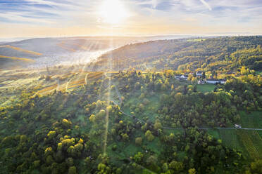 Germany, Baden-Wurttemberg, Drone view of sun rising over autumn landscape of Remstal valley - STSF03649