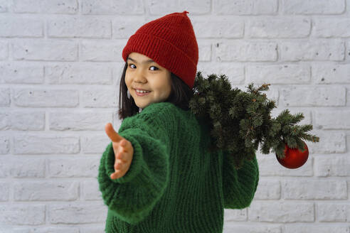 Lächelndes Mädchen gestikuliert mit Weihnachtsbaum - IEF00207