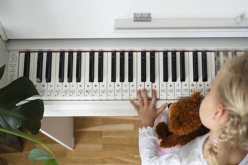 Girl with teddy bear learning piano at home - SVKF00687