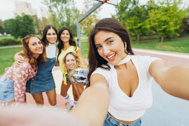 Glückliche Frau nimmt Selfie mit Freunden am Sportplatz - MEUF08414