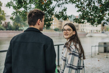 Junge Frau mit Brille steht neben ihrem Freund auf dem Fußweg - VSNF00100