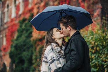 Junges Paar küsst sich auf den Mund unter dem Regenschirm - VSNF00102