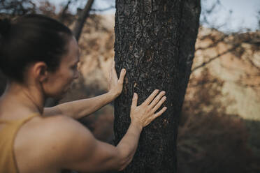 Woman touching burnt tree trunk in forest - DMGF00895