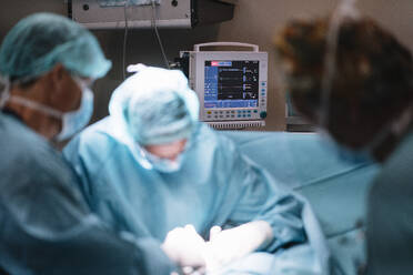 Unerkennbare Chirurgen bei einer Operation im dunklen Raum - ADSF40350