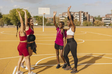 Young women standing with hands raised in sports court - JCCMF07870