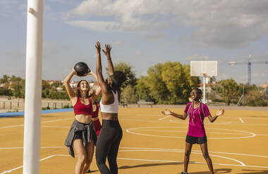 Glückliche Freunde spielen Basketball auf dem Sportplatz - JCCMF07871