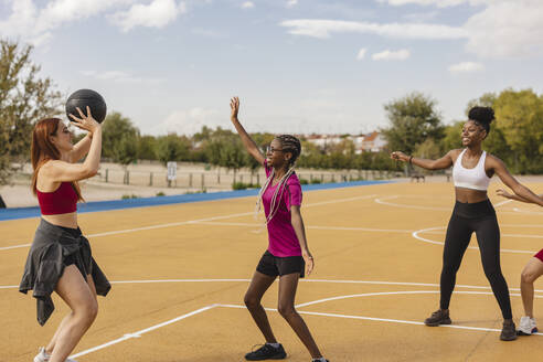 Frau wirft Basketball zu Freunden auf dem Sportplatz - JCCMF07875