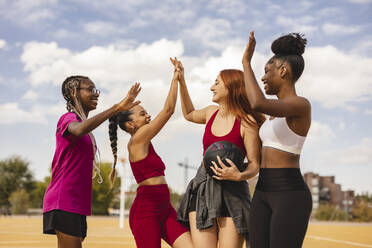 Glückliche multirassische Freunde beim High-Five auf dem Sportplatz - JCCMF07882