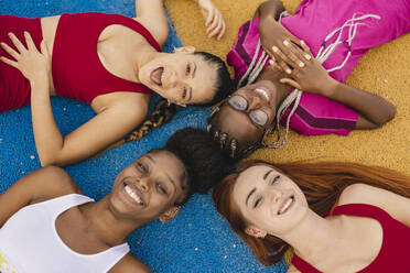 Cheerful friends lying down in sports court - JCCMF07894