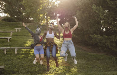 Frauen mit Tiermaske springen im Park - JCCMF07930