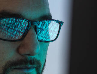 Hacker wearing eyeglasses with reflection of binary codes - ABRF01021