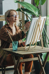 Blonde Frau mit Pinsel malt auf Leinwand - VSNF00137