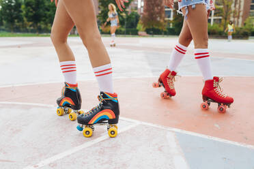 Frau mit Freunden beim Rollschuhlaufen auf dem Sportplatz - MEUF08428