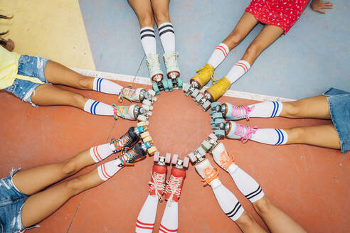 Legs of women wearing roller skates making circle at sports court - MEUF08446