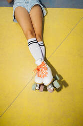 Legs of woman wearing roller skates lying on sports court - MEUF08528