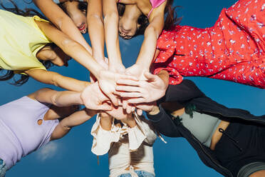 Female friends stacking hands at dusk - MEUF08542