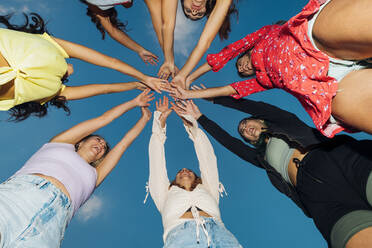 Happy friends with arms raised under blue sky at dusk - MEUF08543