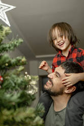 Sohn und Vater haben Spaß am Weihnachtsbaum zu Hause - ANAF00502