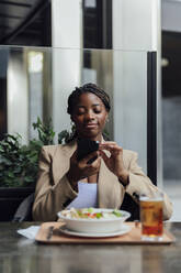 Smiling businesswoman surfing net sitting at cafe - PGF01351