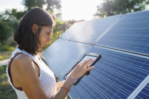 Mature woman using tablet PC by solar panels - MRRF02501