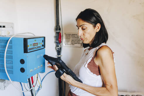 Ältere Frau benutzt Tablet-PC am Wechselrichter eines Solarkraftwerks - MRRF02509