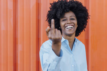 Happy woman in afro hairstyle showing middle finger - JSMF02483
