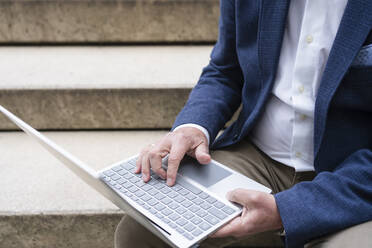 Geschäftsmann mit Laptop auf einer Treppe sitzend - SVKF00738