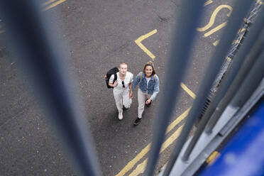 Lesbisches Paar, das zusammen auf einer städtischen Straße spazieren geht und nach oben schaut - ASGF03030