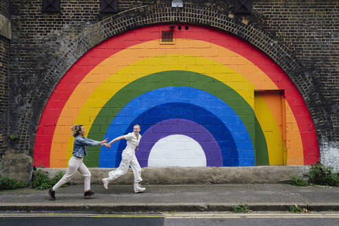 Unbekümmertes lesbisches Paar, das sich an den Händen hält und auf dem Fußweg läuft - ASGF03058