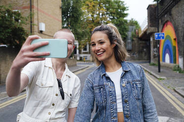 Nicht-binäre Person, die ein Selfie mit ihrem Smartphone auf der Straße macht - ASGF03066