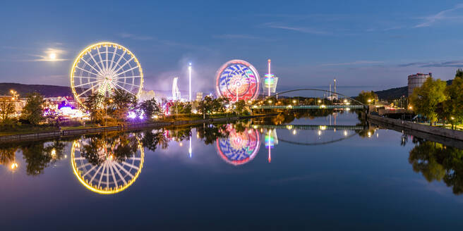 Germany, Baden-Wurttemberg, Stuttgart, Amusement park rides glowing in riverside festival area at night - WDF07135