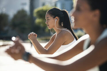 Young woman with friend exercising on sunny day - JSRF02296