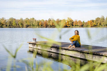 Frau sitzt vor dem See am Steg - DIGF19295