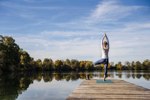 Frau übt Yoga auf einem Steg am See - DIGF19328