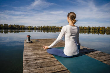 Frau praktiziert Meditation vor einem See - DIGF19341