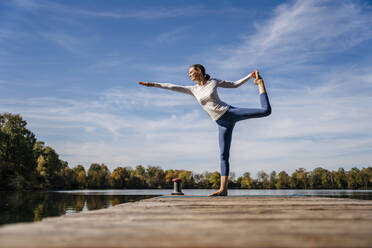 Woman practicing stretching exercise on jetty - DIGF19348