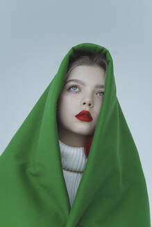 Nachdenkliches Mädchen, eingewickelt in grünes Samttuch vor weißem Hintergrund - IEF00237